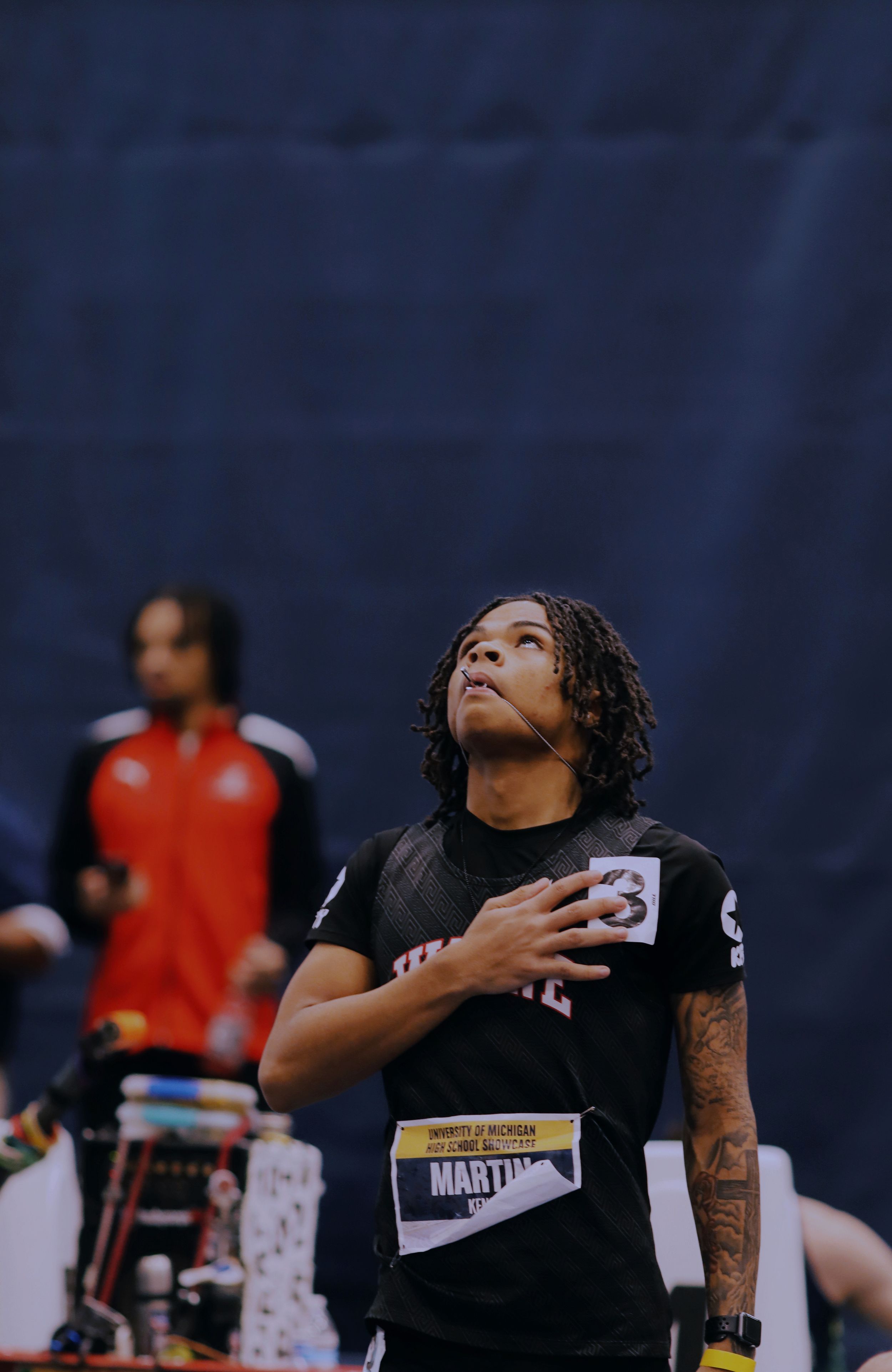 An athlete in a black jersey looks upward during what appears to be a pre-game moment at a sporting event.