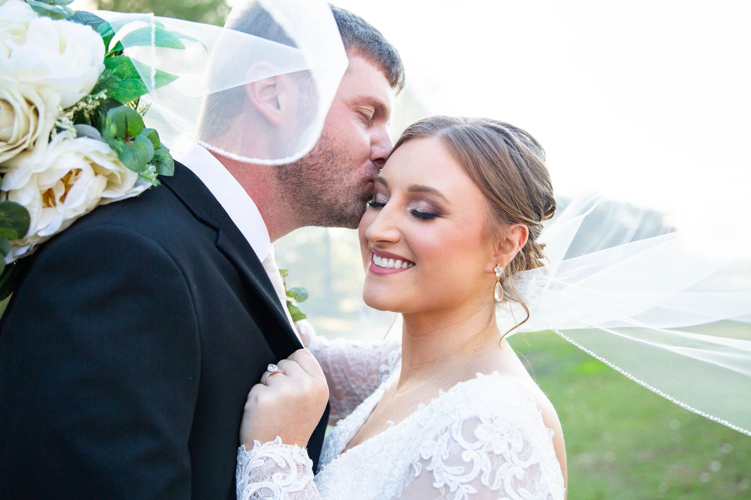 groom kisses bride as she smiles