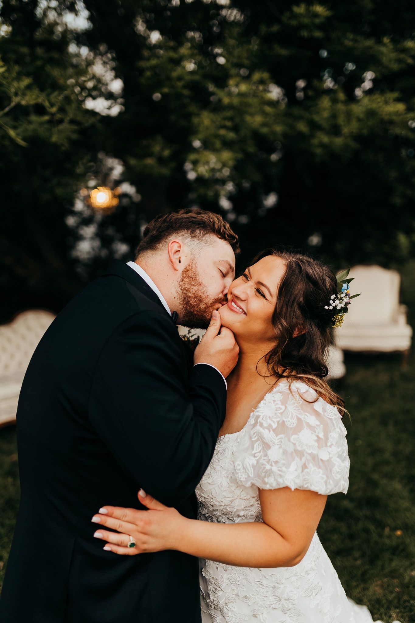 A tender wedding moment captured outdoors as newlyweds share an intimate kiss in a natural setting.