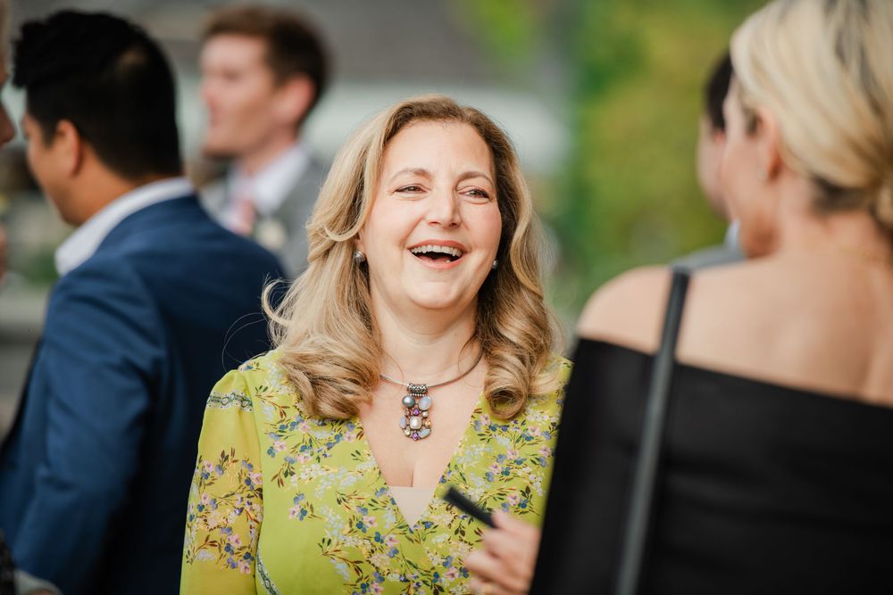 Group of guests enjoying conversation and laughter at an outdoor social event.