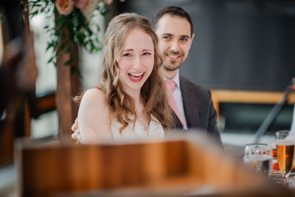 Wedding celebration scene with guests seated at tables during reception with festive lighting and decor.