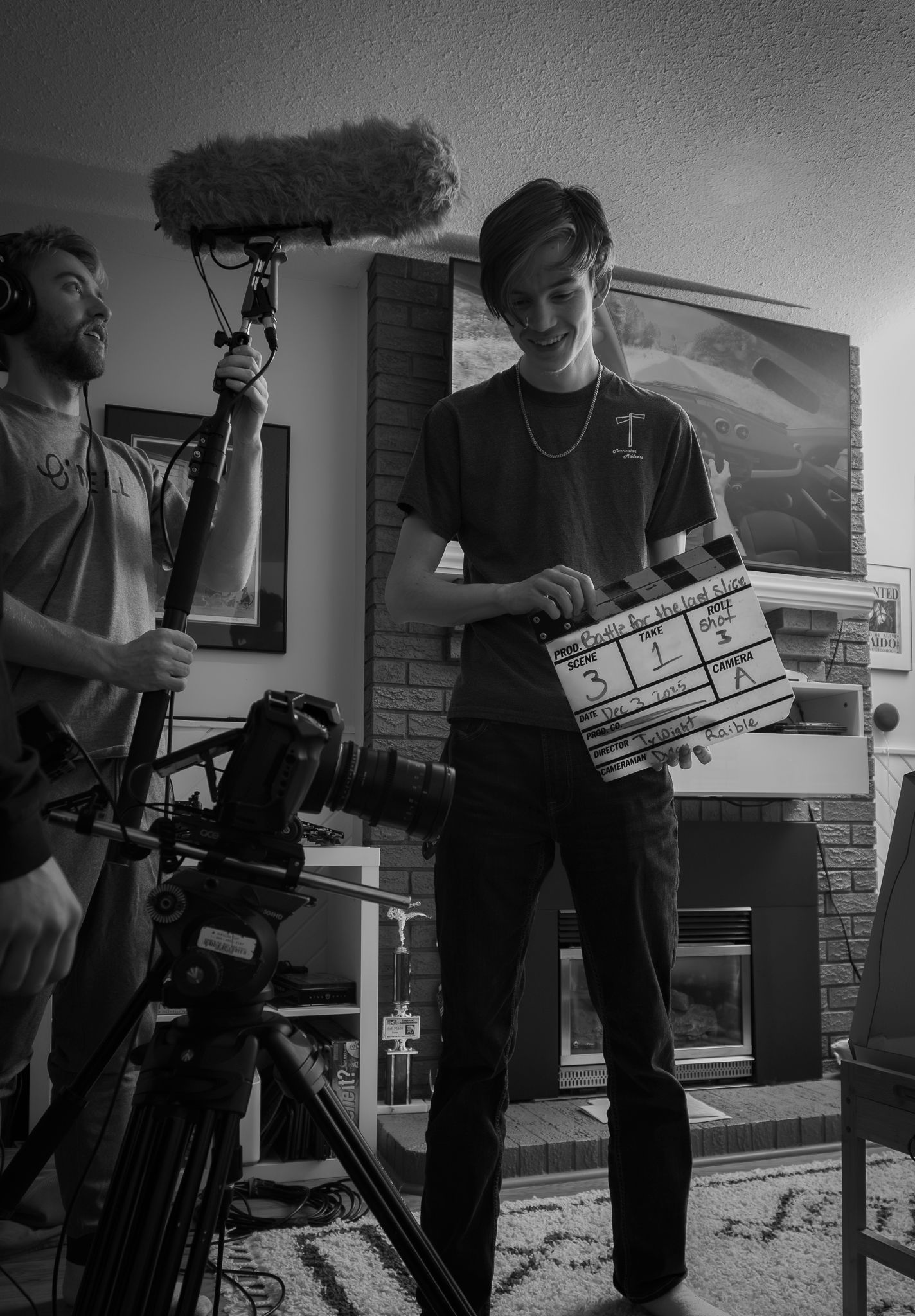 Black and white film production scene showing crew members with camera equipment and clapperboard.
