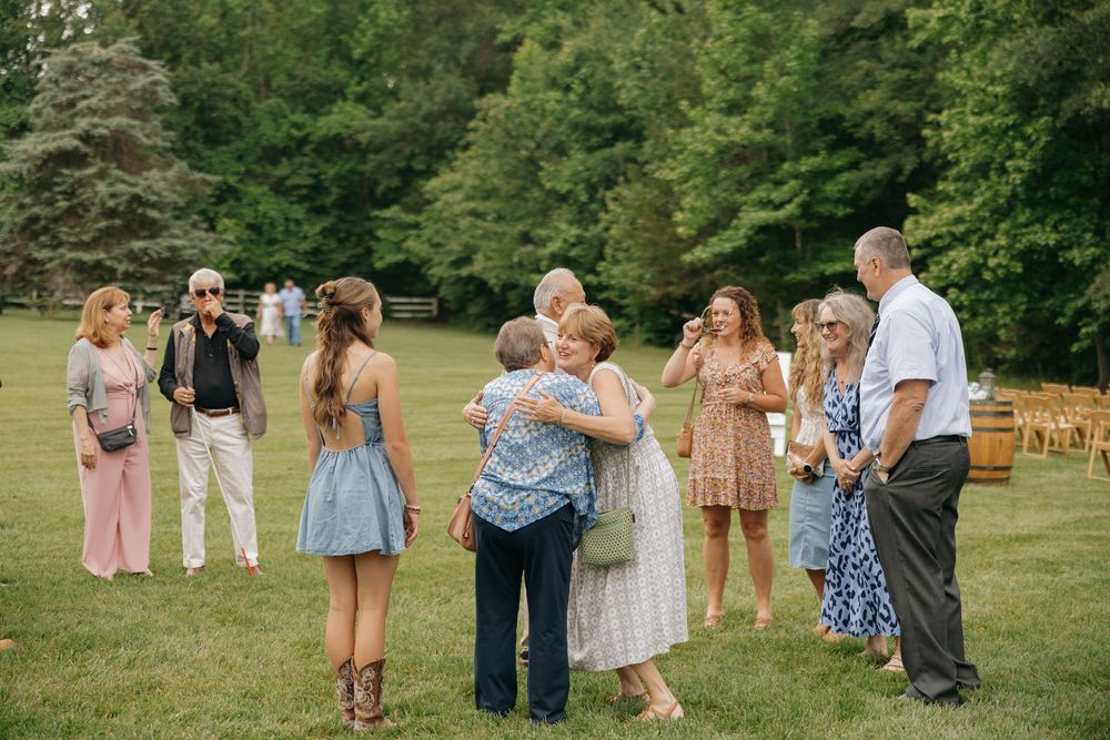 Wedding guests form a line outdoors on a grassy lawn during a summer celebration.