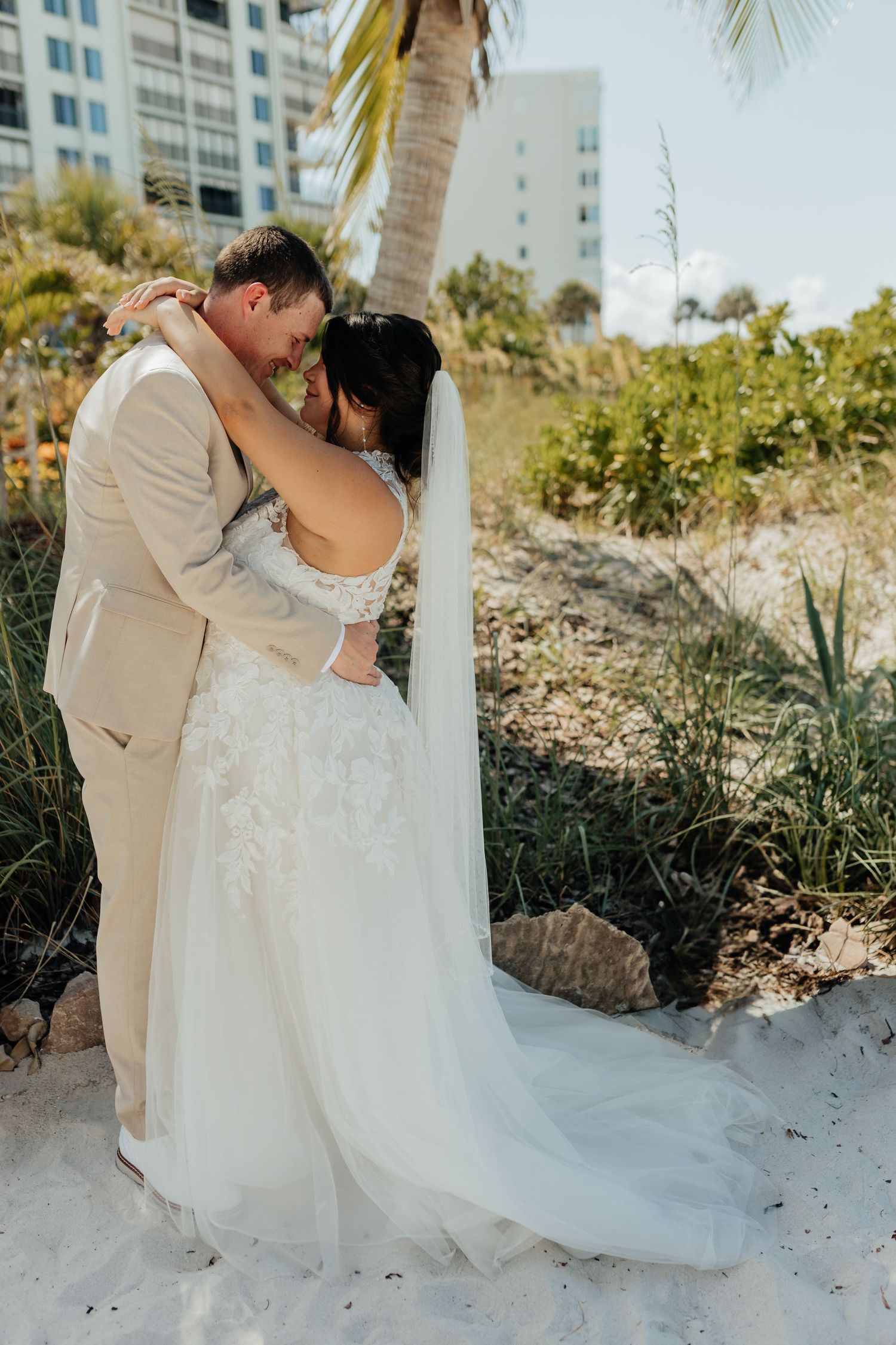 Bride and groom kissing on the beach during a wedding photography session.