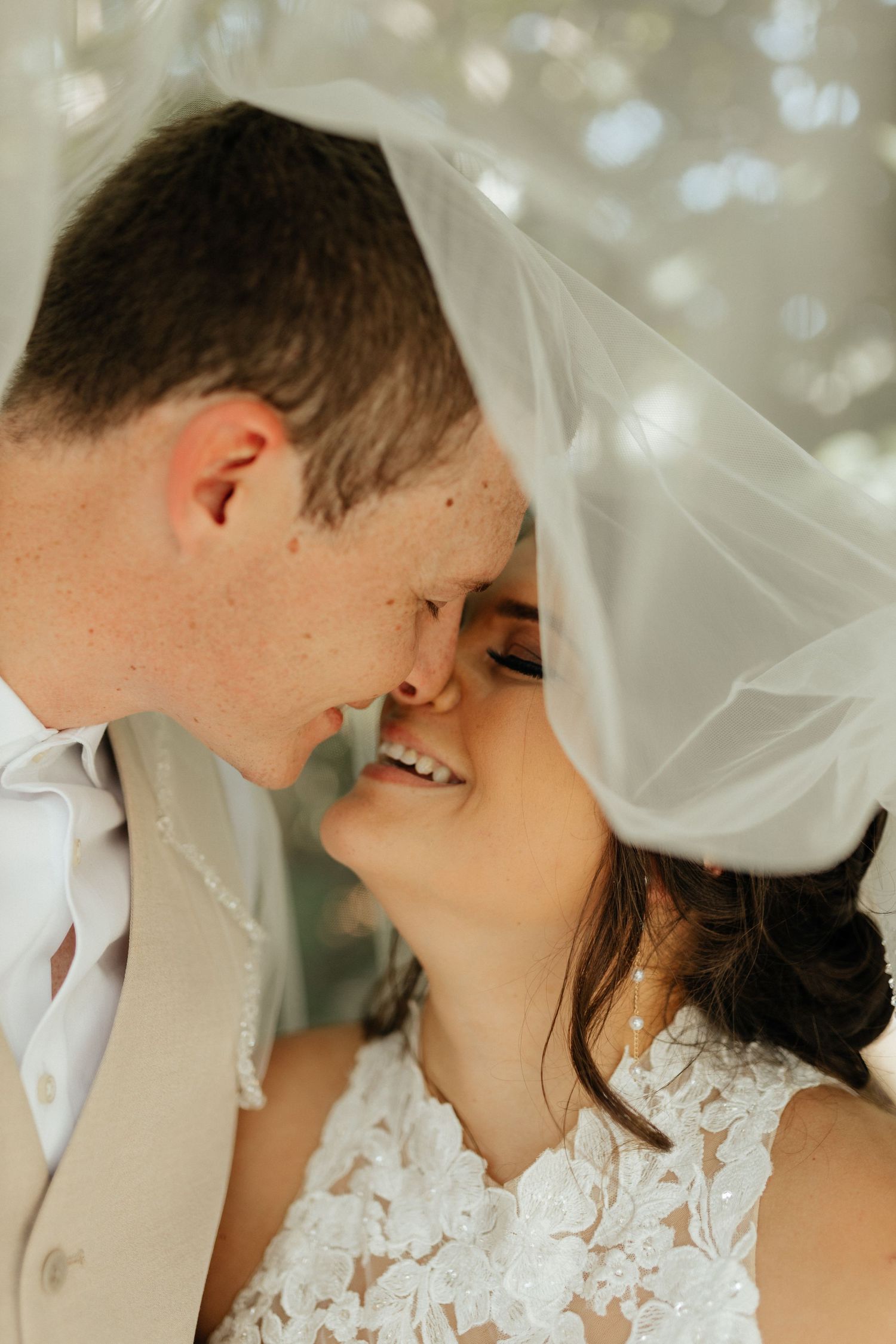 Bride and groom kissing on the beach during a wedding photography session.