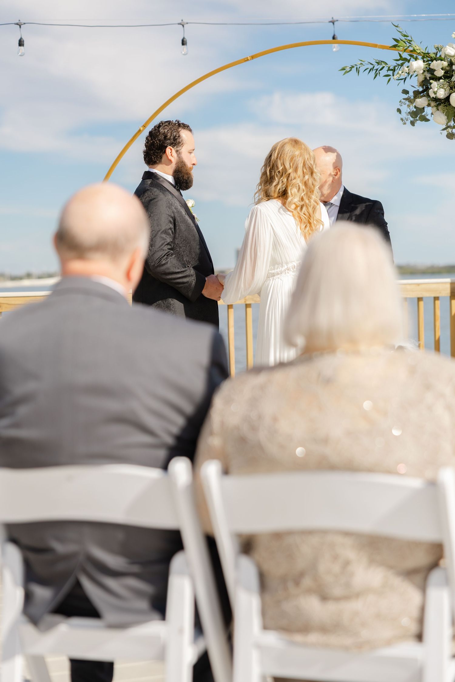 Bride and groom standing together during a wedding ceremony viewed from the guests’ perspective.