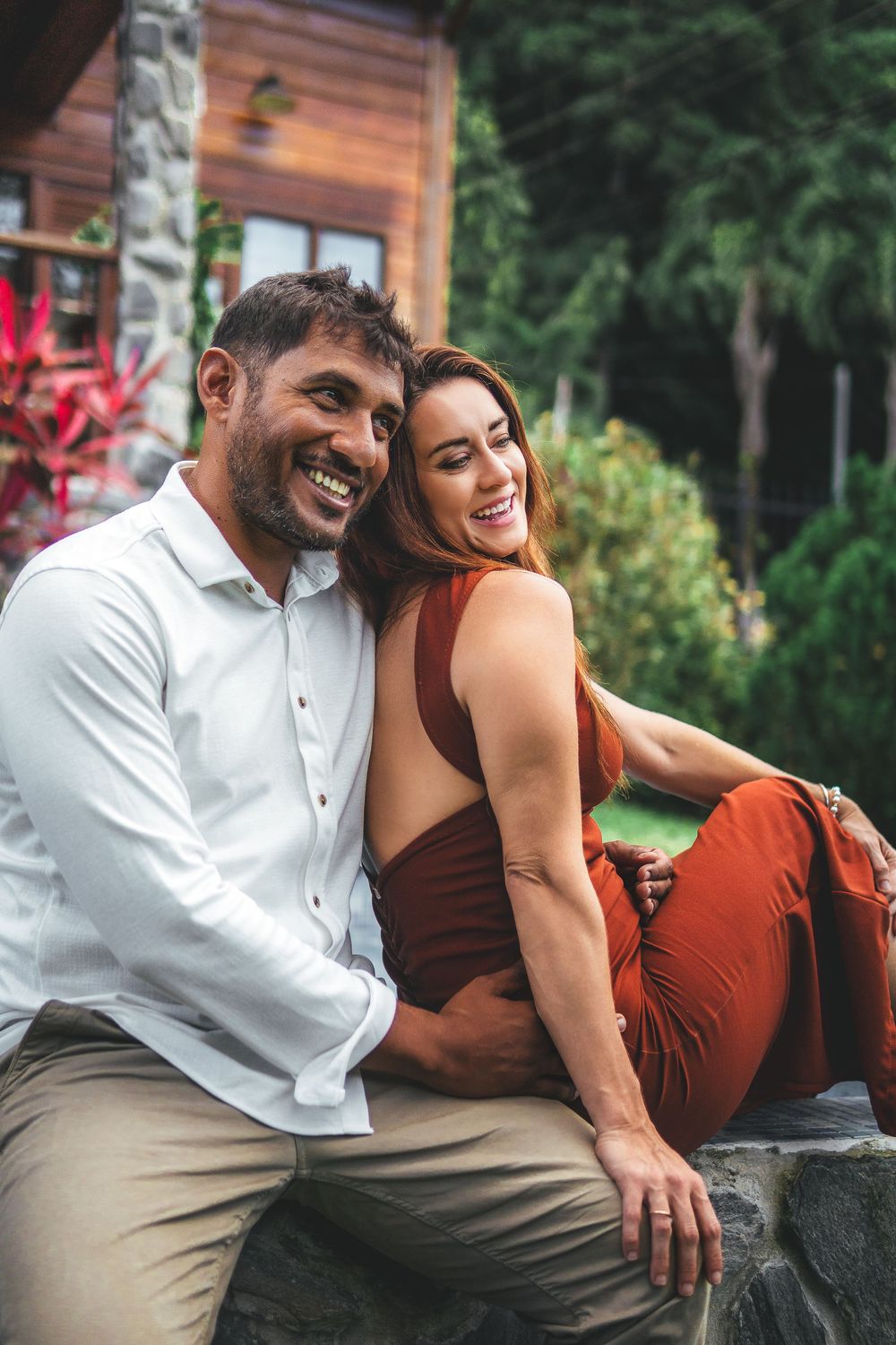 Couple smiling together during a relaxed outdoor portrait session in a lush garden.