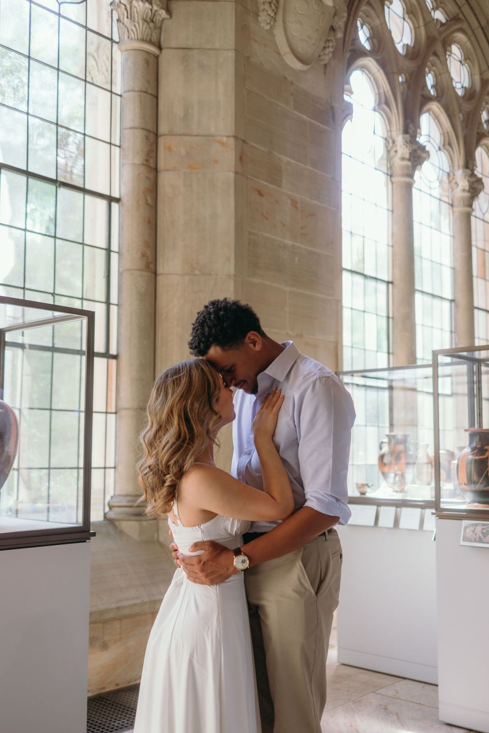 A tender moment captured in an elegant hallway with arched windows and natural light.