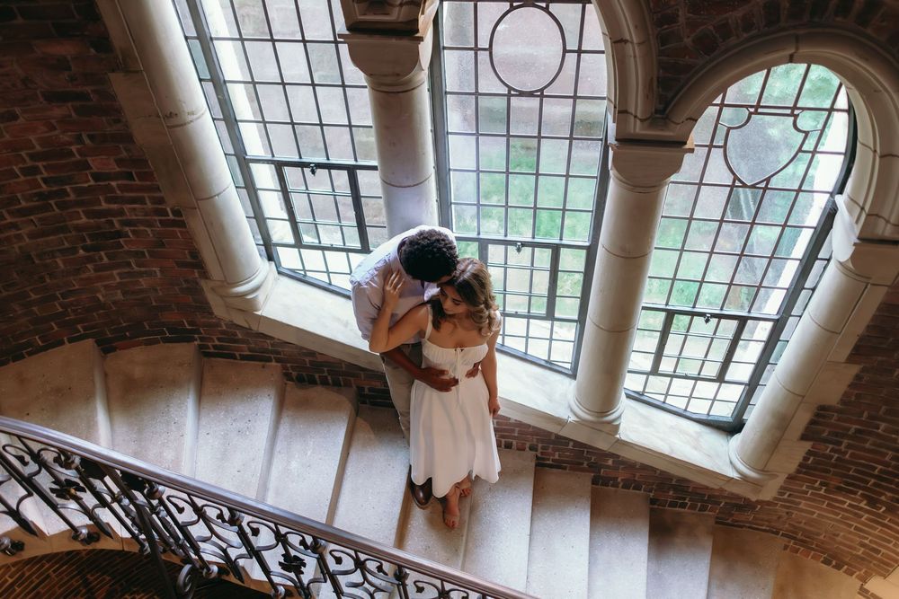 A romantic scene unfolds beneath ornate stained glass windows in a historic building.