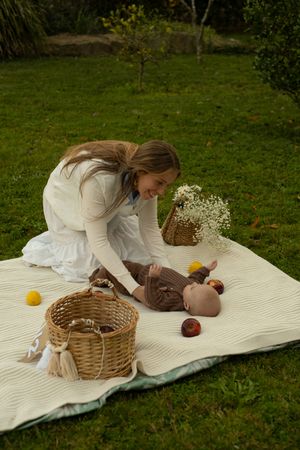 A picturesque picnic setup on grass with a white blanket and woven basket.