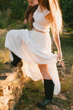 Long white dress flowing in golden sunlight against a natural outdoor backdrop.