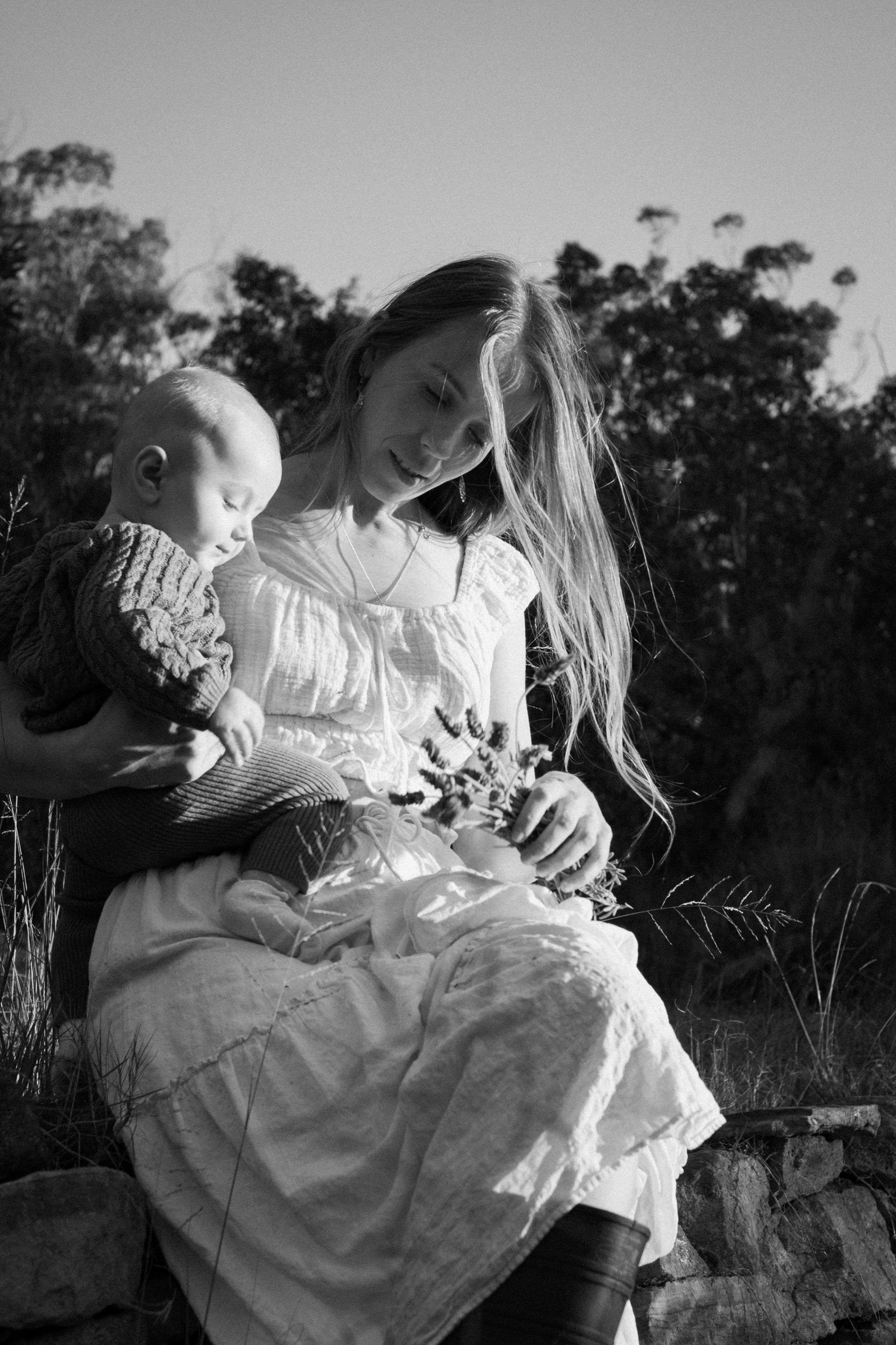 Black and white photograph capturing intimate moments in billowing white dresses outdoors.