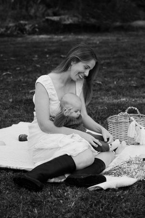 Black and white photograph of a relaxed picnic scene with white blanket and basket on grass.