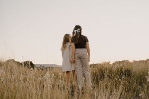 Peaceful figures standing in a golden field during sunset, creating silhouettes against the warm sky.