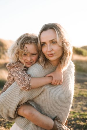 Tender embrace captured in warm sunset lighting outdoors.