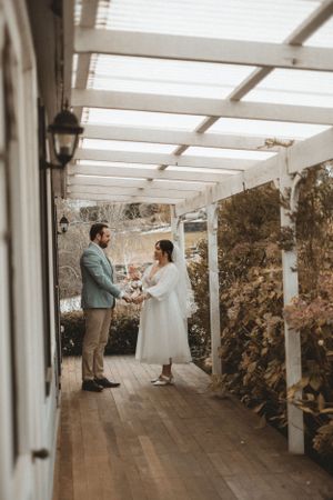 Wedding couple dancing in a rustic covered patio with natural lighting.