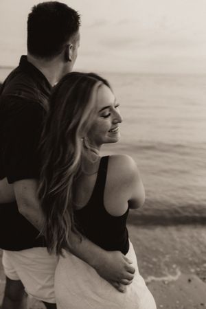 Couple embracing on a beach in a romantic black and white photo.