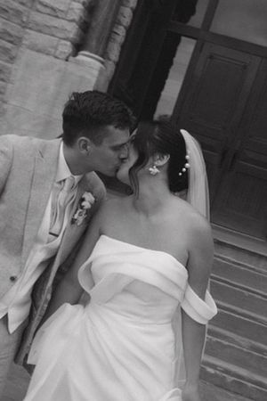 Bride and groom kissing on church steps in a classic black and white photo.