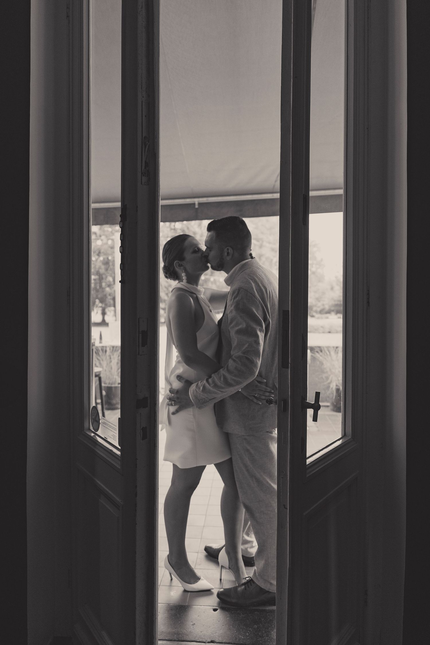 A romantic silhouette of a couple embracing viewed through an open doorway.