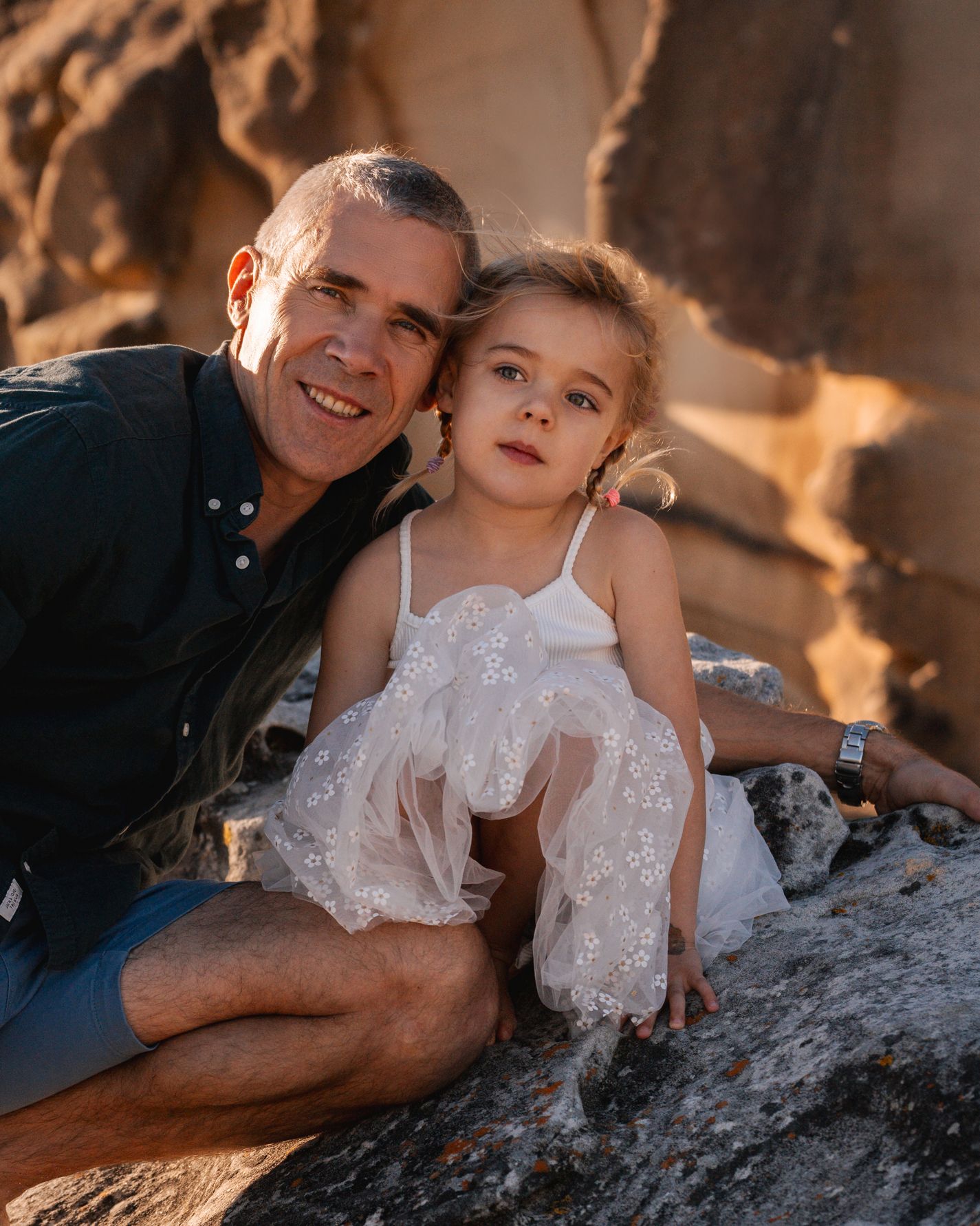 daughter and father sitting on the rocks during a family photoshoot in sydney