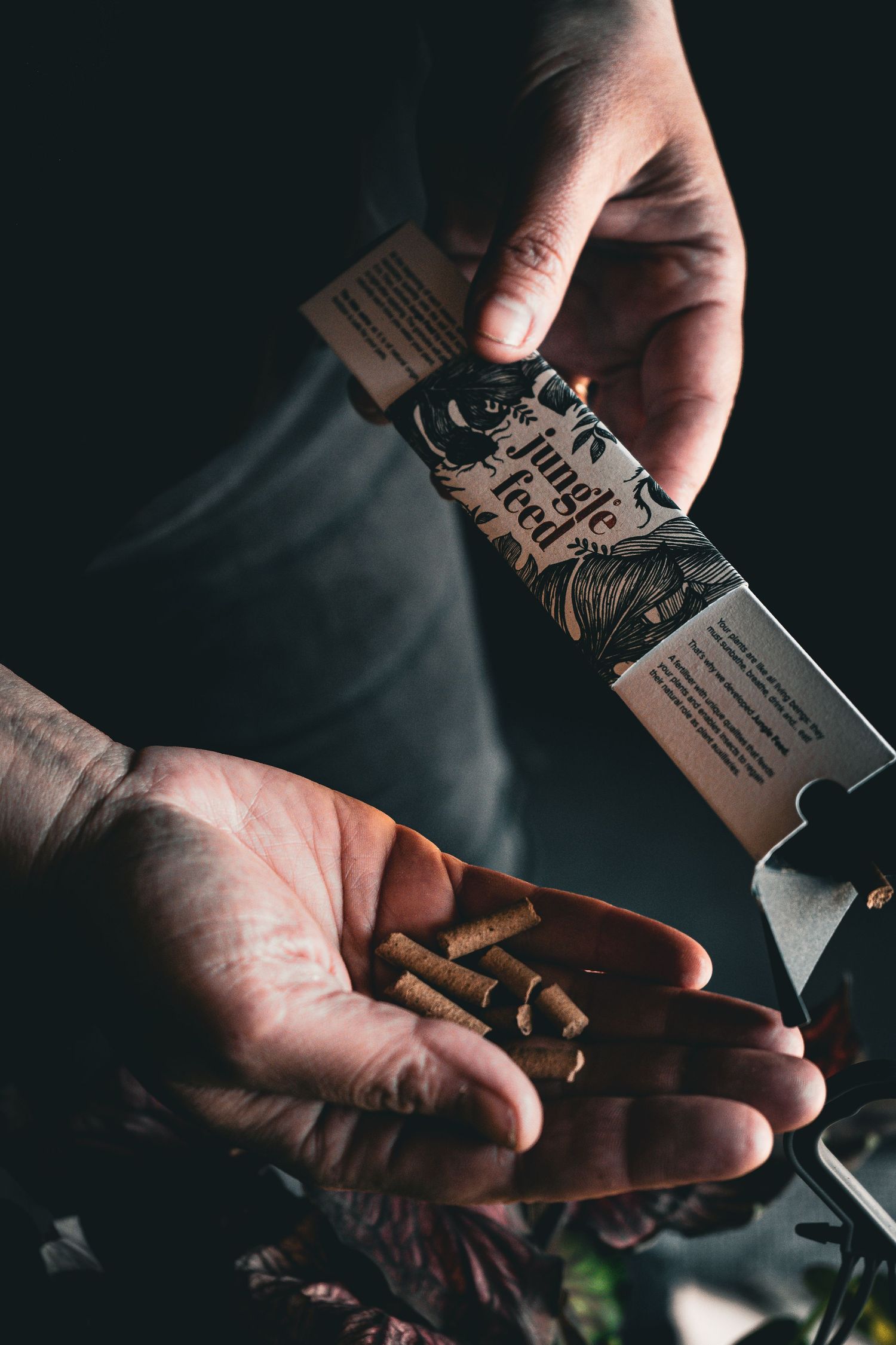 a photograph of hands holding plant food pellets and the cardboard packaging