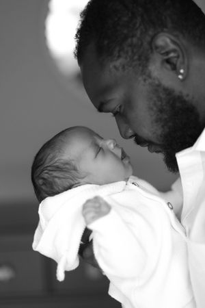 Intimate black and white moment of parent sharing tender moment with newborn baby.