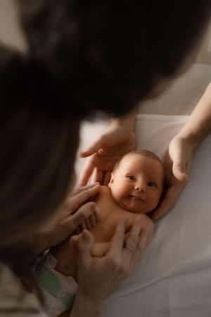 Overhead view of gentle hands cradling a smiling baby during a tender moment.