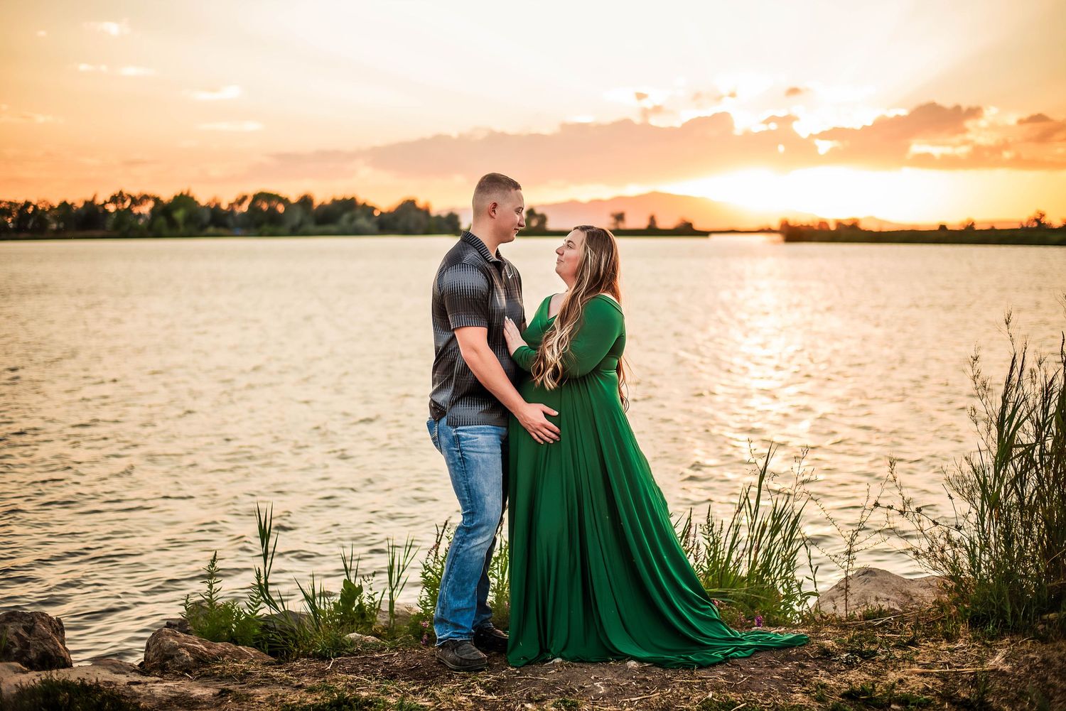 couple embracing by the lake at sunset during a maternity photoshoot in Utah