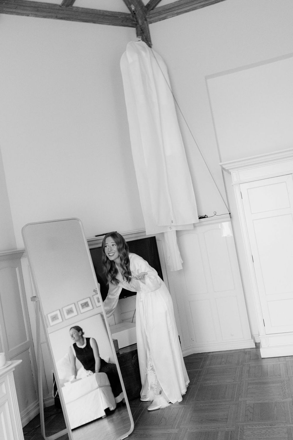 A series of black and white photos showing a figure in white fabric moving through an empty room with wooden floors.