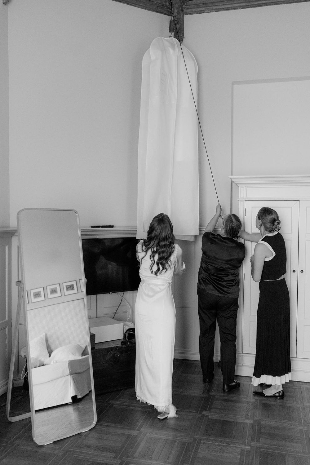 A black and white photo series showing people in white garments moving around a gallery space.