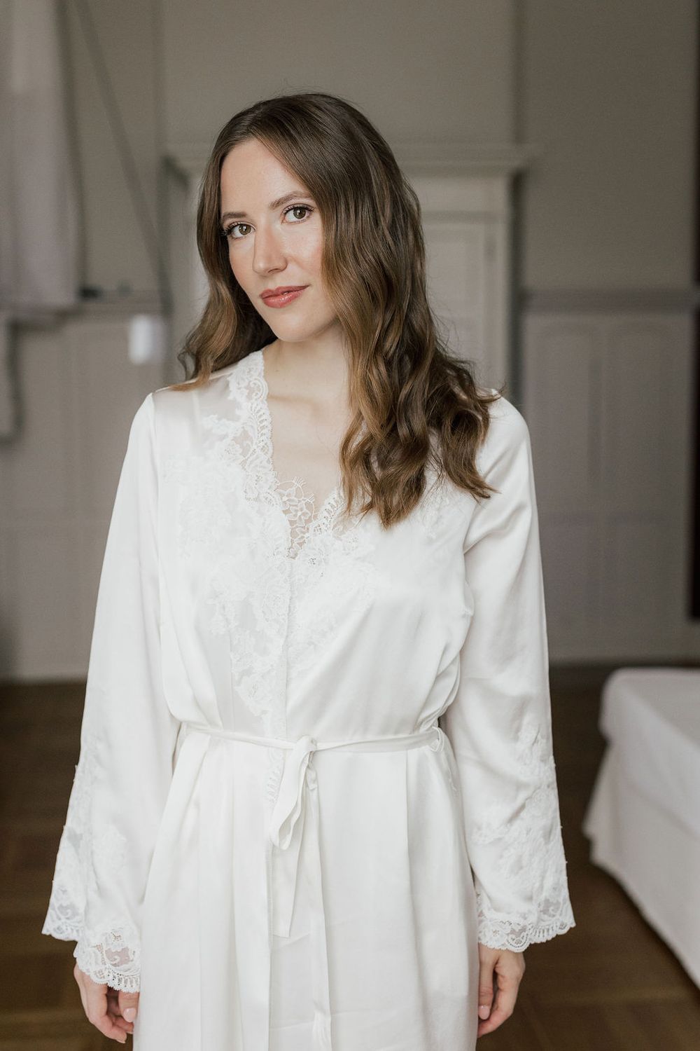 Elegant white lace-trimmed robe with bell sleeves photographed in a bright indoor setting.