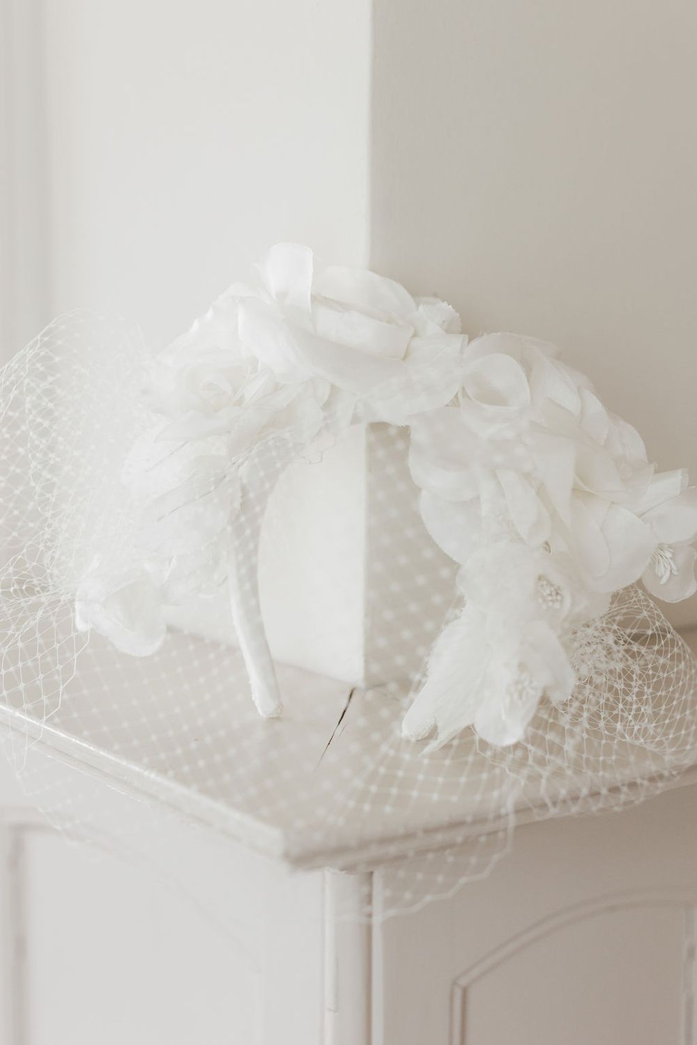 A delicate white bridal veil with lace trim and floral appliques is elegantly draped and photographed in soft lighting.
