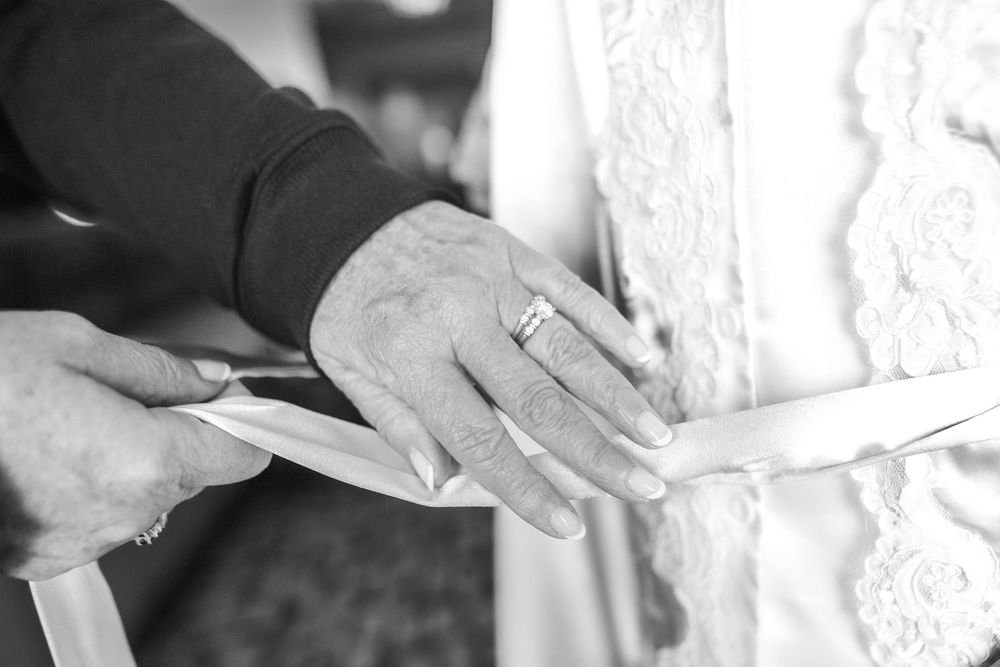 A close-up black and white photograph of hands writing with a fountain pen on paper.
