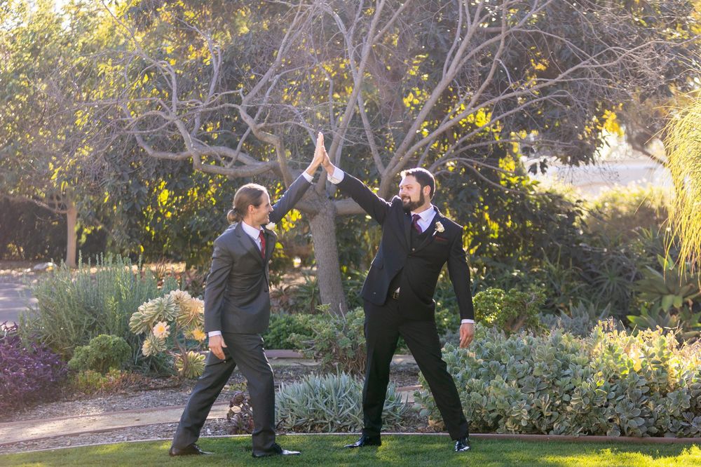 Wedding party performs playful jumping sequence in a garden setting during golden hour.