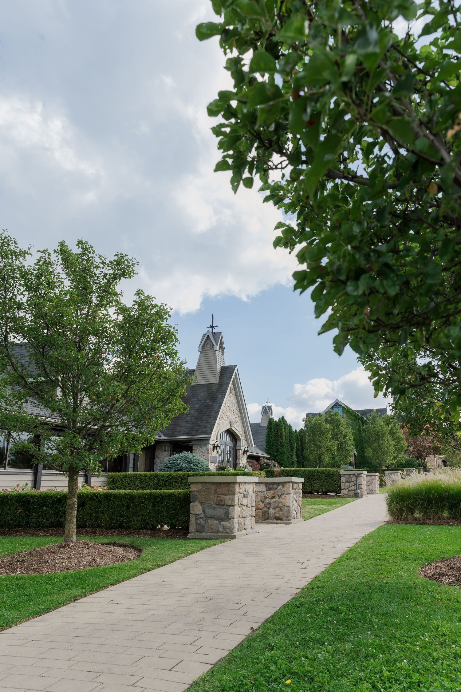 Stone pathway leads through manicured garden to elegant wedding venue entrance at Vineland Estates Winery.