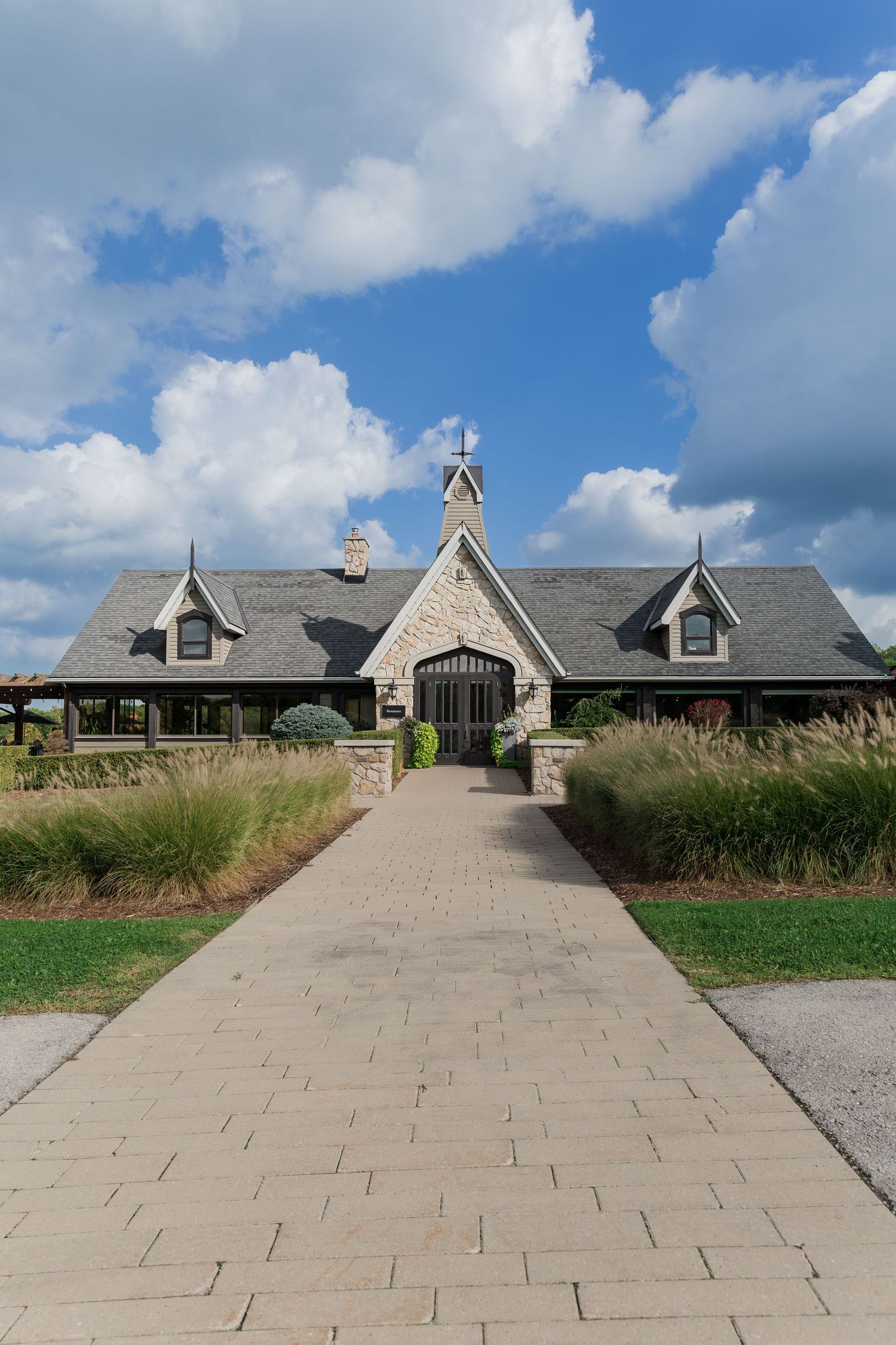 Stone chapel-style building with dormers and peaked roof connected by a paved walkway at Vineland Estates Winery.