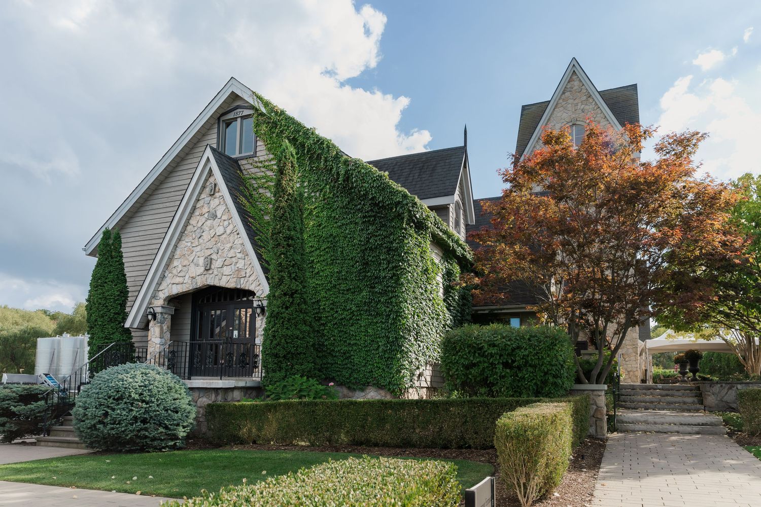 Stone and ivy-covered winery buildings with autumn trees and landscaped pathways at Vineland Estates Winery.