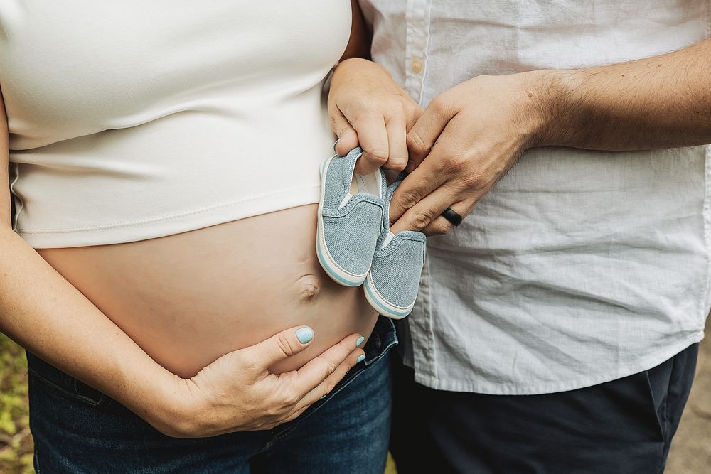Close-up maternity photo series showing pregnant belly and hands touching in white clothing against natural backdrop.