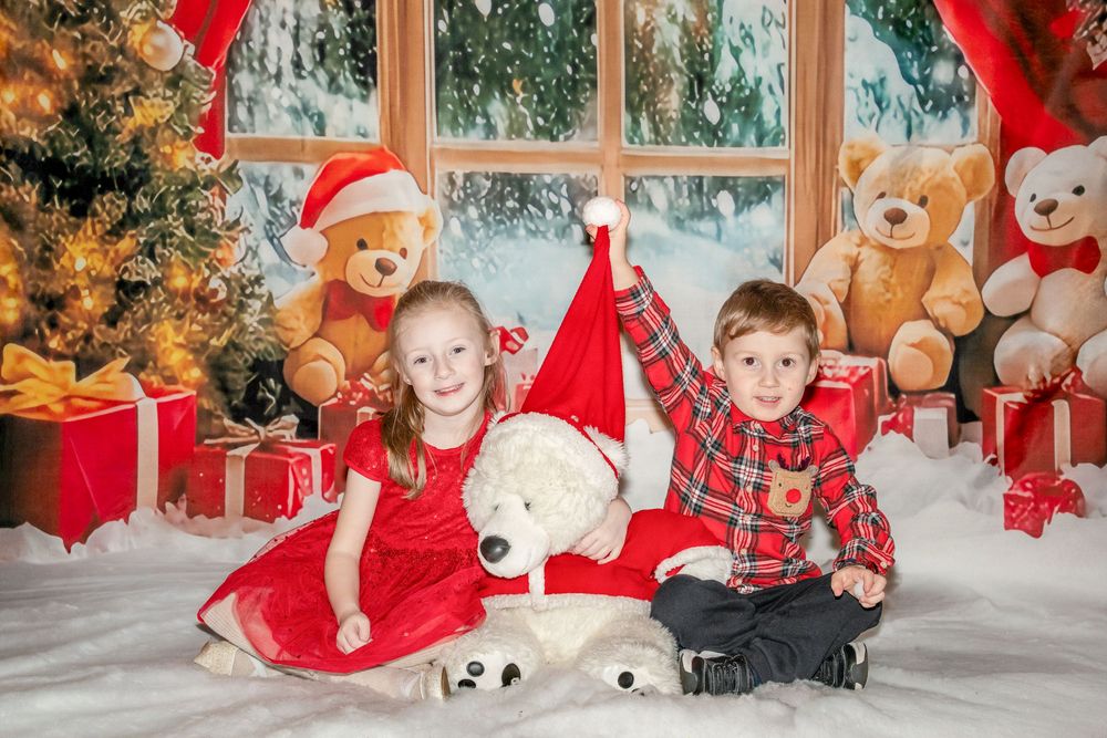 Festive holiday scene with teddy bears, red ribbons, and Christmas decorations arranged by a window.