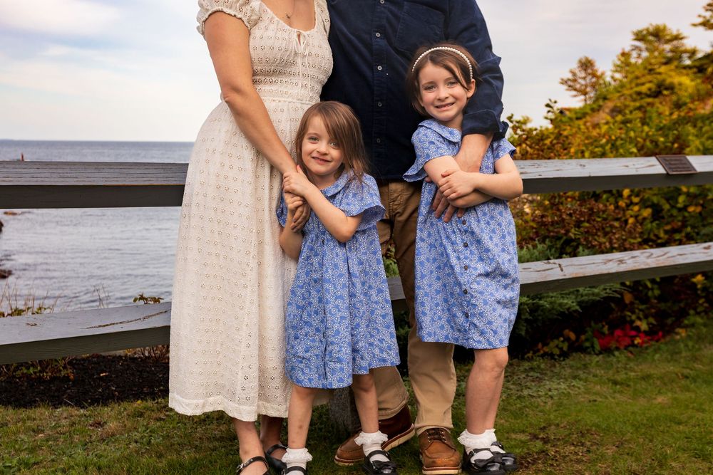 Children in coordinating blue and white outfits playing together outdoors during a family photoshoot.