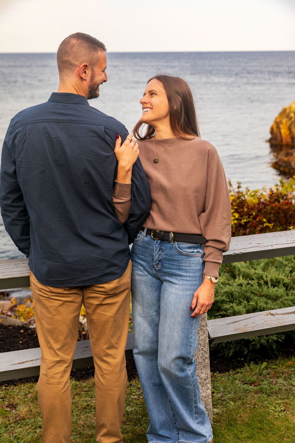 Couple enjoying a romantic moment while overlooking the ocean from a coastal viewpoint on an autumn day.