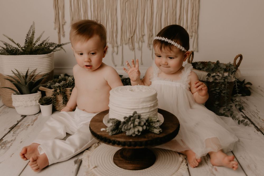 A series of five photos showing a baby's first birthday cake smash session with a rustic white cake and natural decor.