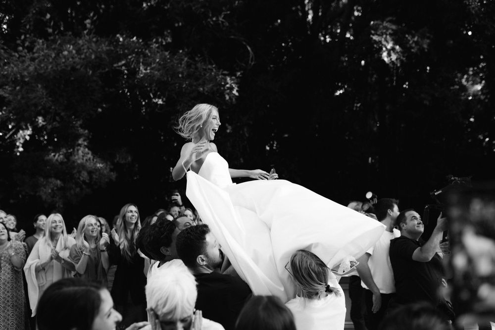 Black and white photo of wedding guests dancing and celebrating on a dance floor.