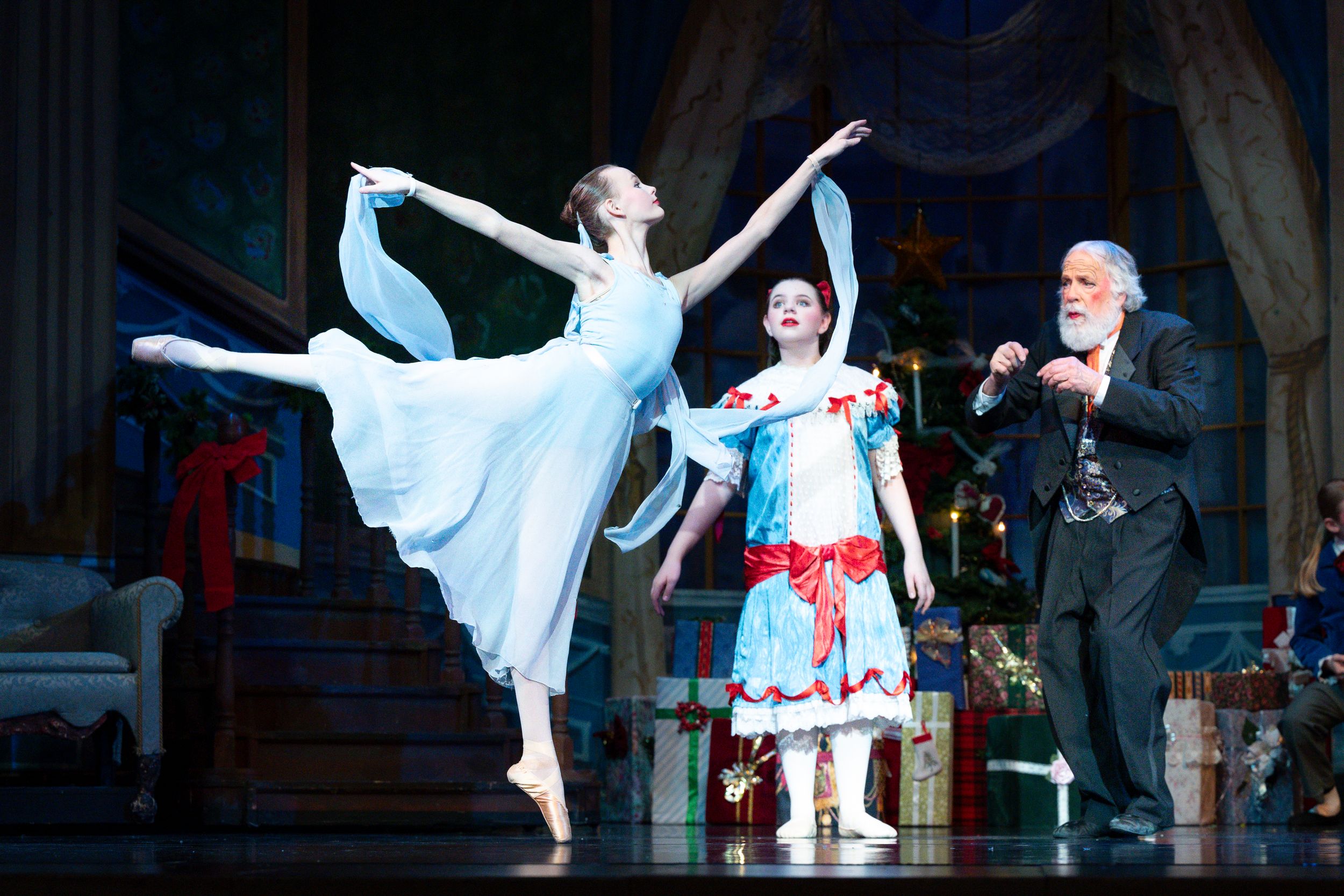 Ballet dancers perform on stage in elegant white costumes during a classical dance performance.