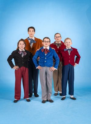 Five young performers in vintage-style clothing with bow ties pose confidently against a bright blue studio backdrop.
