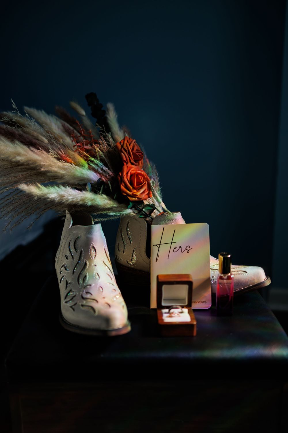 Wedding shoes and decorative boxes arranged artistically in dramatic low-key lighting with feather accents.