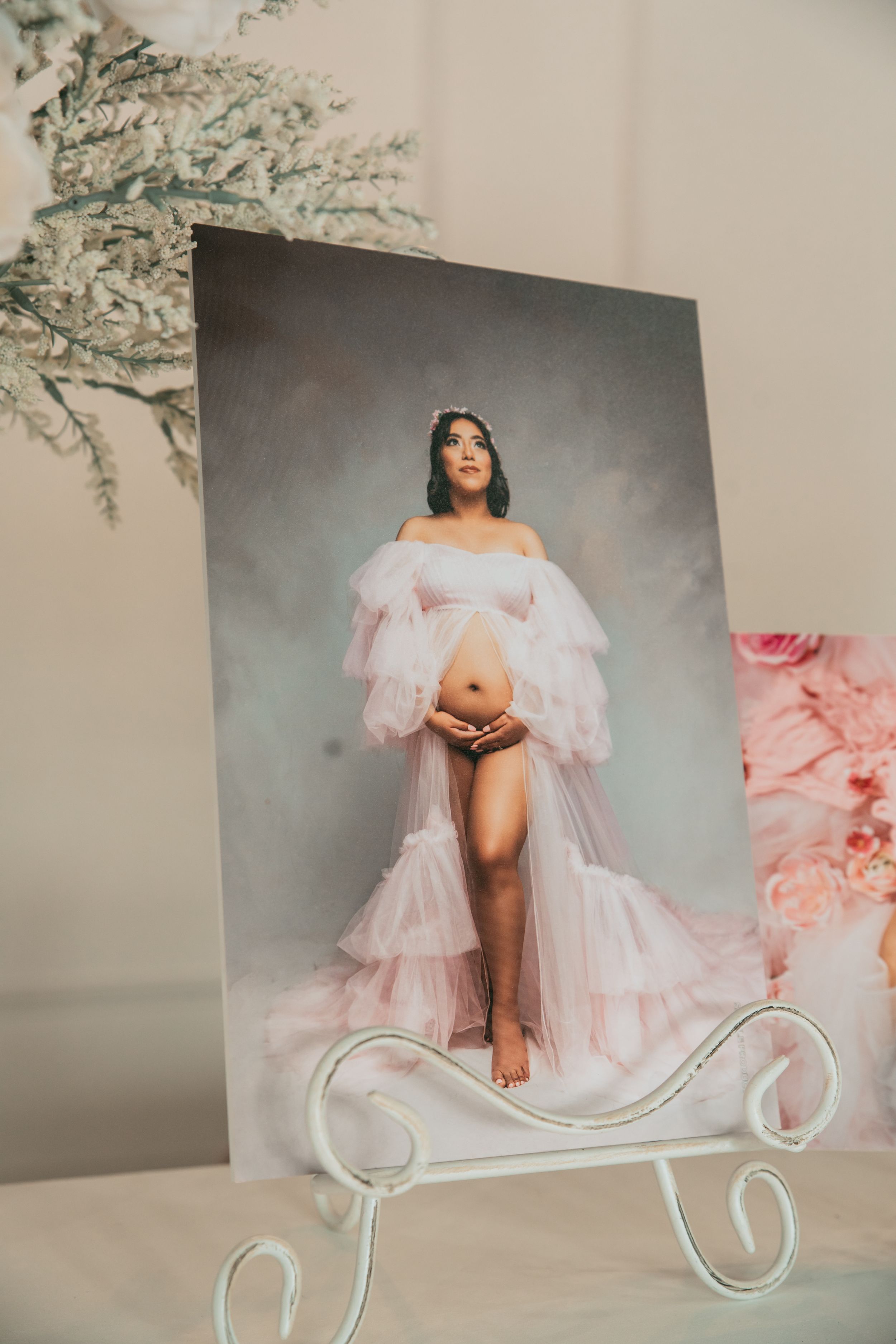 Artistic maternity photography display with soft pink tulle fabric and white decorative elements.