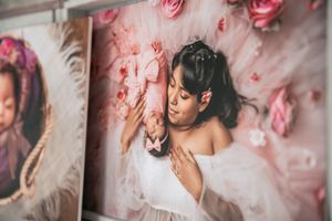 Pink roses and floral decorations adorn a studio wall display with soft romantic lighting.