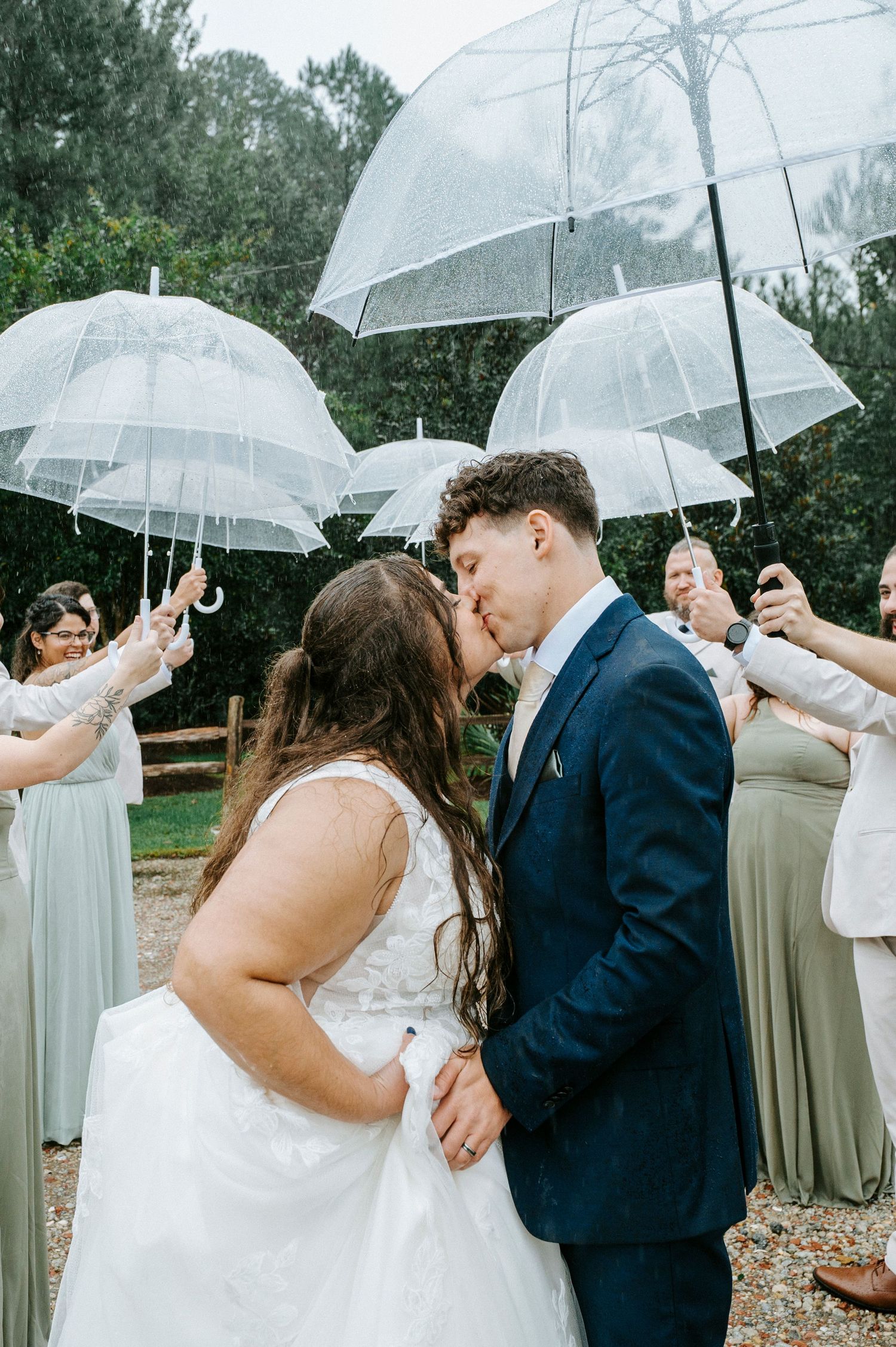 Romantic wedding sequence showing couple sharing a kiss under clear umbrellas with bridesmaids in beige dresses looking on.