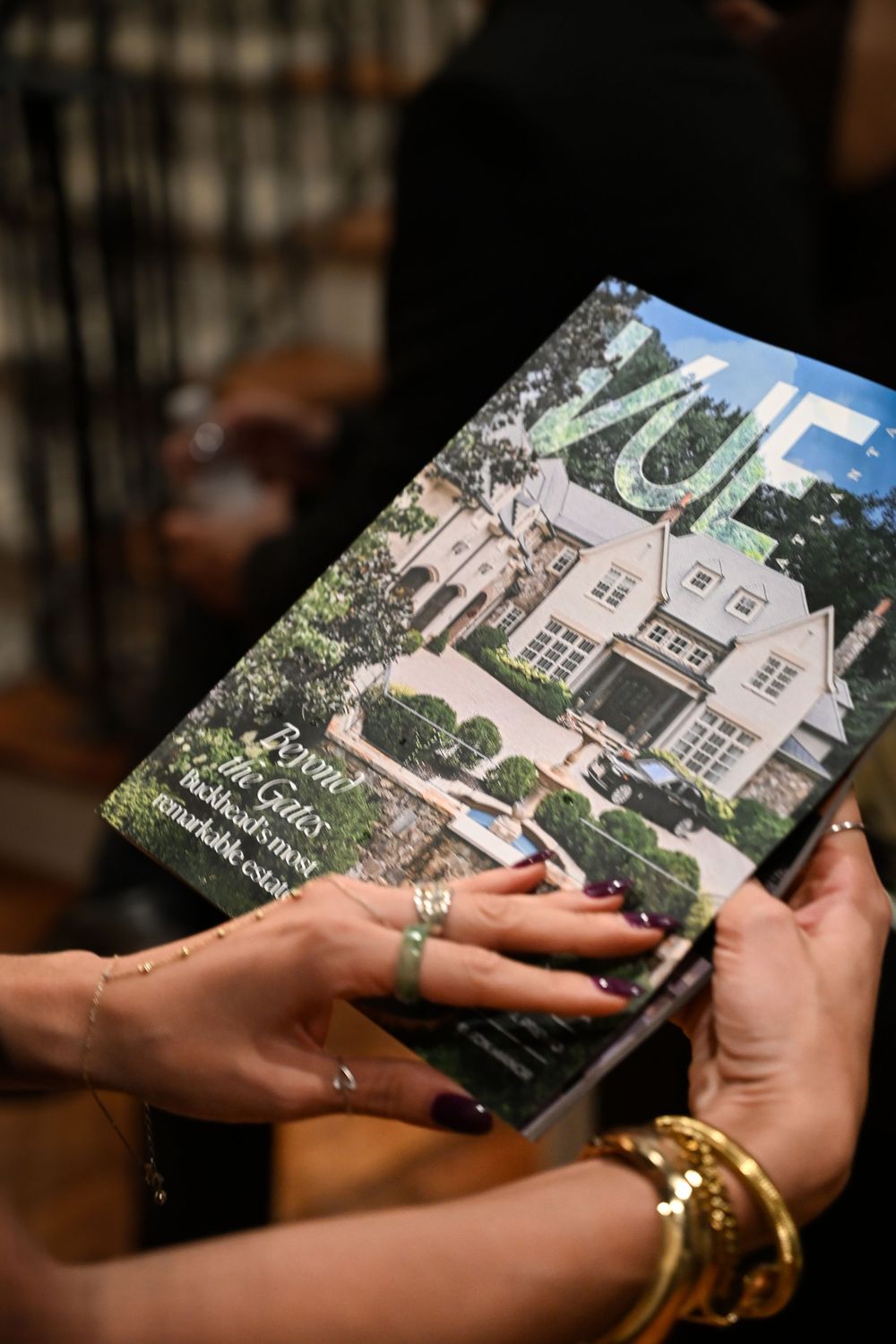 Hands holding and exchanging a brochure showing architectural renderings of a building exterior.